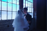 a bride and groom standing in front of a window